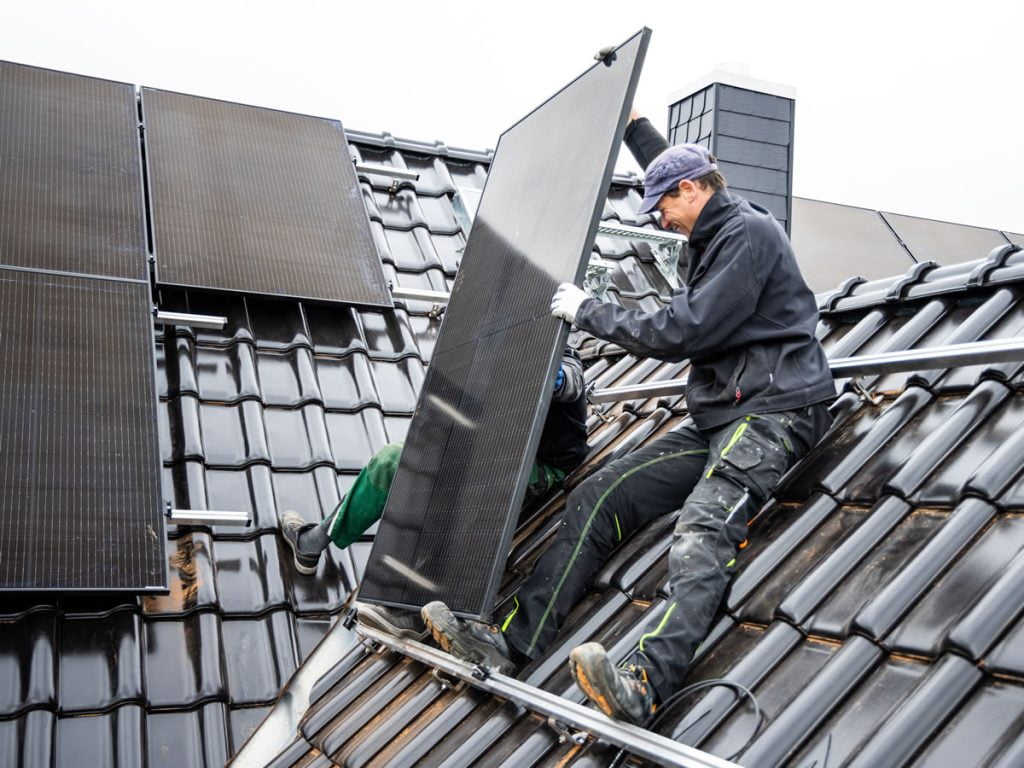 Solar installers fitting solar panels to house roof